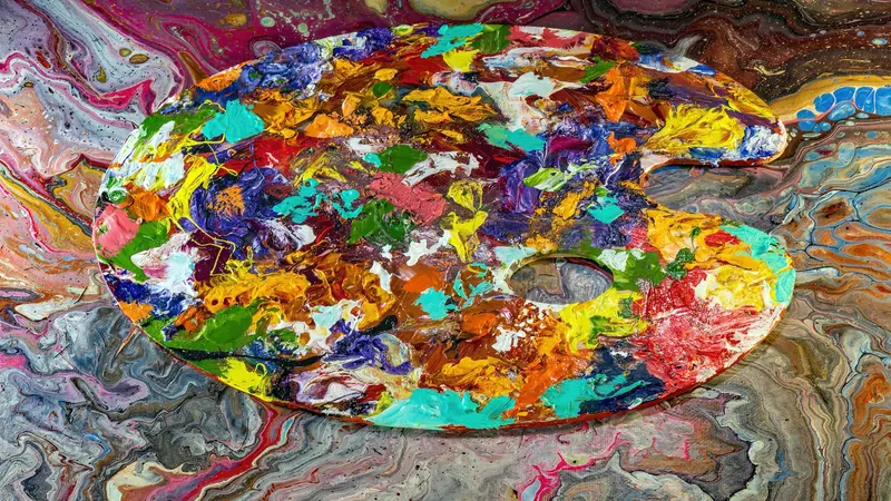 Paleta de pintor coberta de tintas vivas e misturadas sobre uma superfície marmorizada