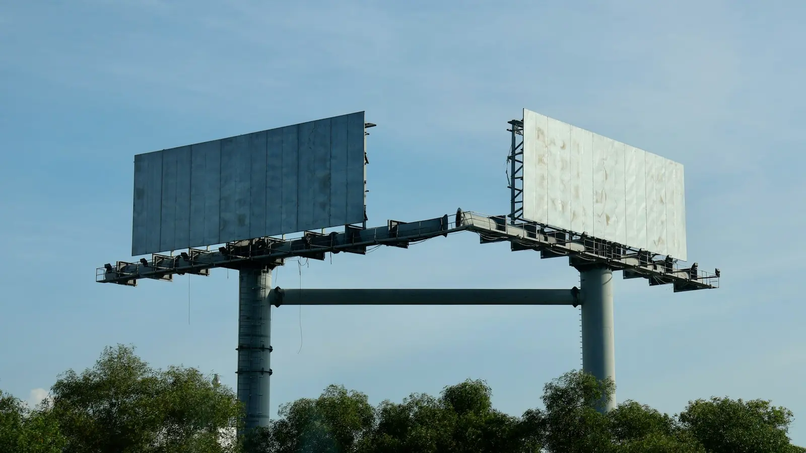 Two empty billboards against a blue sky