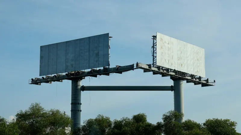 Two empty billboards against a blue sky