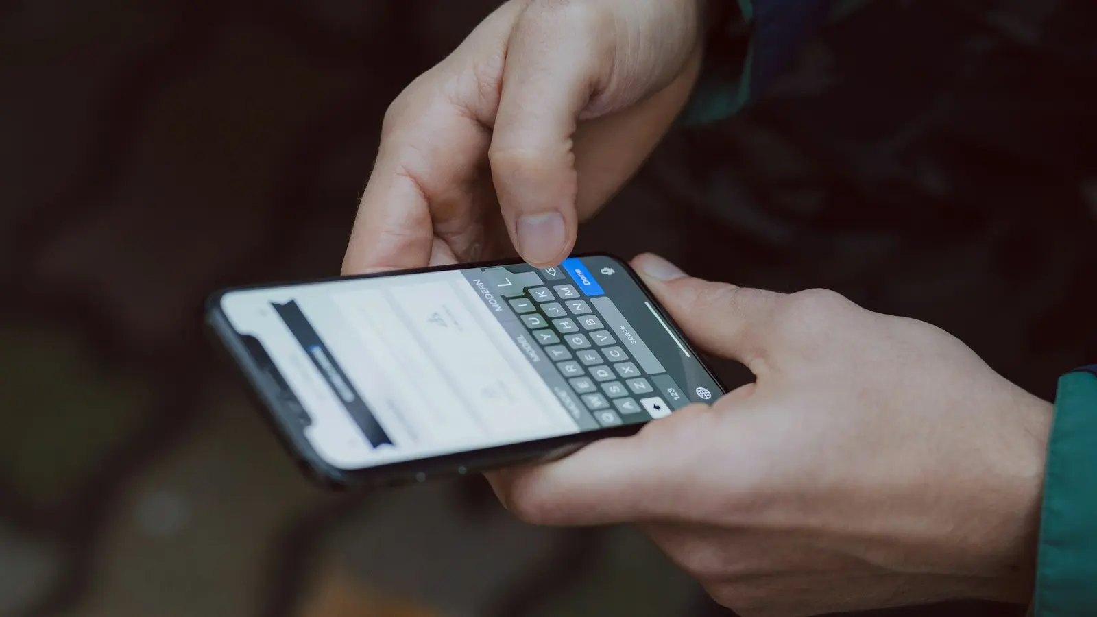 Nahaufnahme von Händen, die eine Nachricht auf einem Smartphone tippen